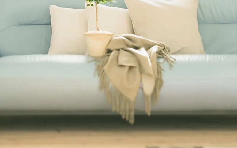 Canapé en tissu clair, coussins et plaid