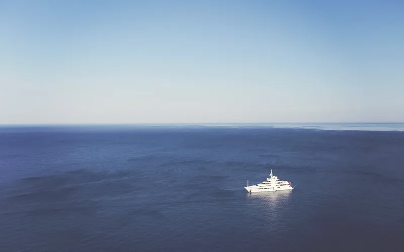 Un yacht au large, sur une mer d’un bleu profond