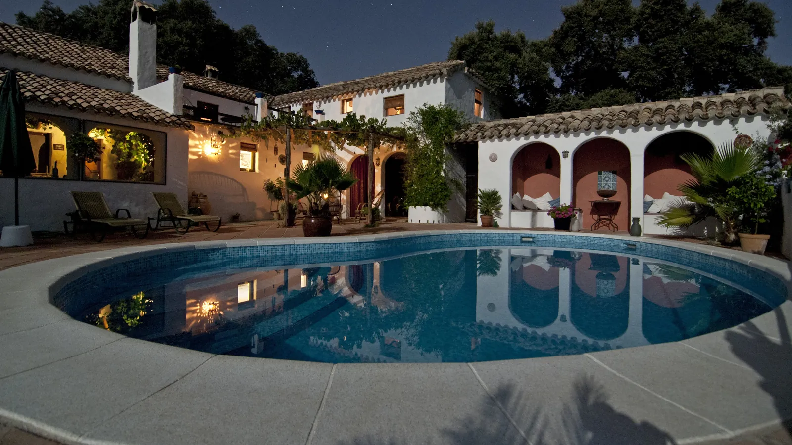 La Grande Bastide à la tombée de la nuit, sa piscine et ses arcades éclairées