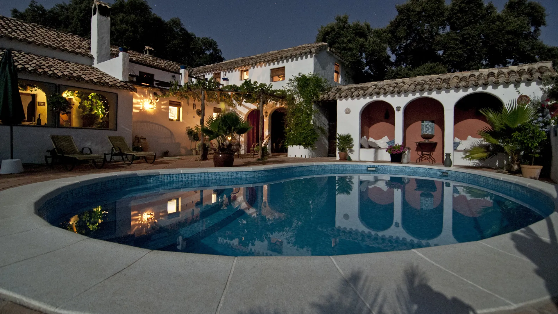 La piscine de La Grande Bastide à la tombée du jour, devant la maison éclairée