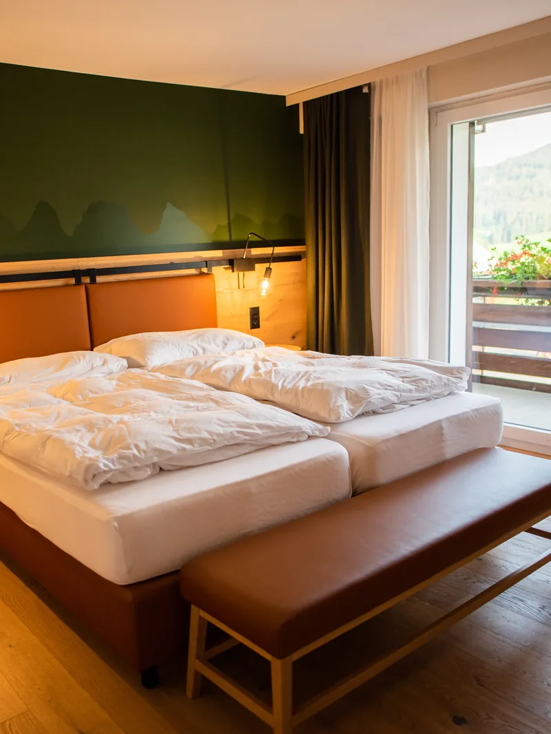 Une chambre de La Grande Bastide, lit fait et banquette en cuir au pied du lit
