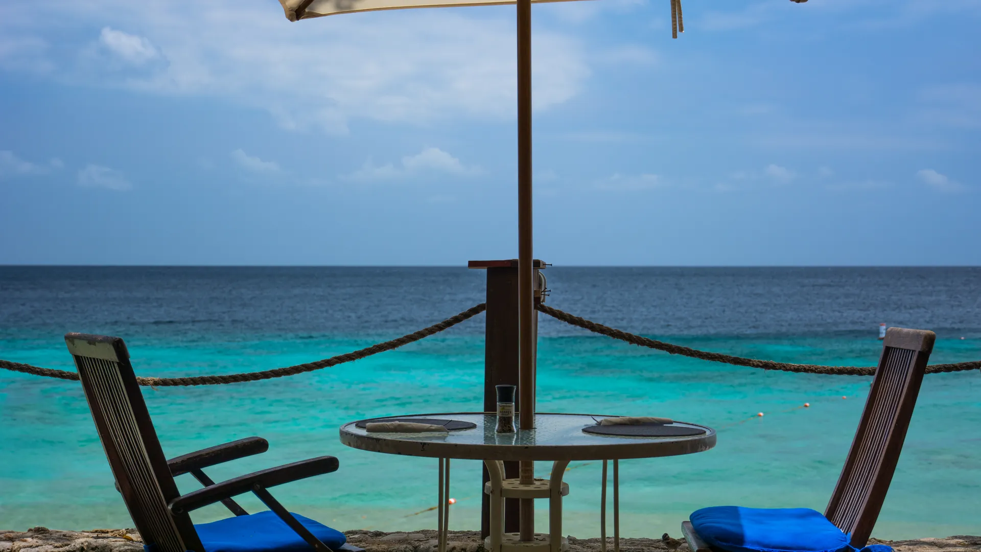 La terrasse de la Villa Horizon, table et parasol face à la mer turquoise