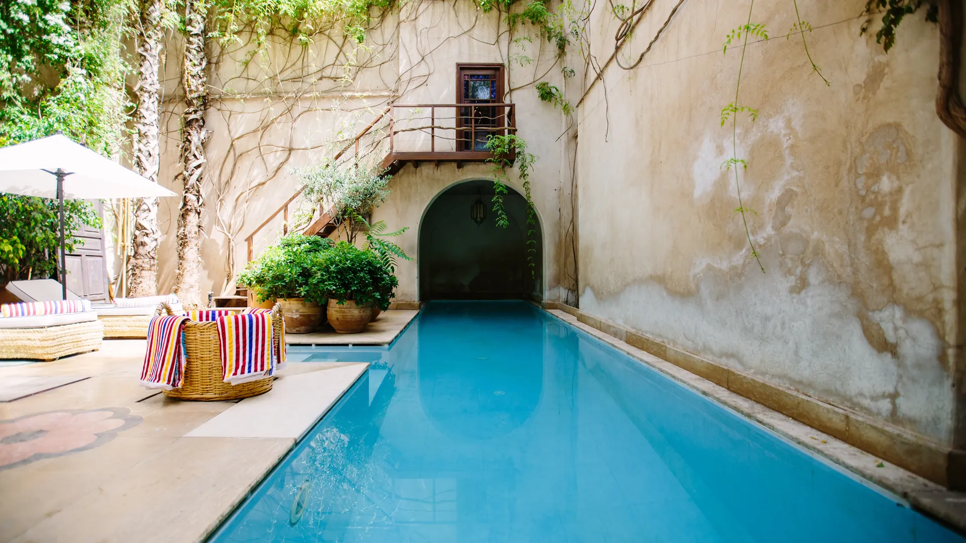 La piscine de la Villa des Pins, dans une cour fleurie au pied d'un mur ancien