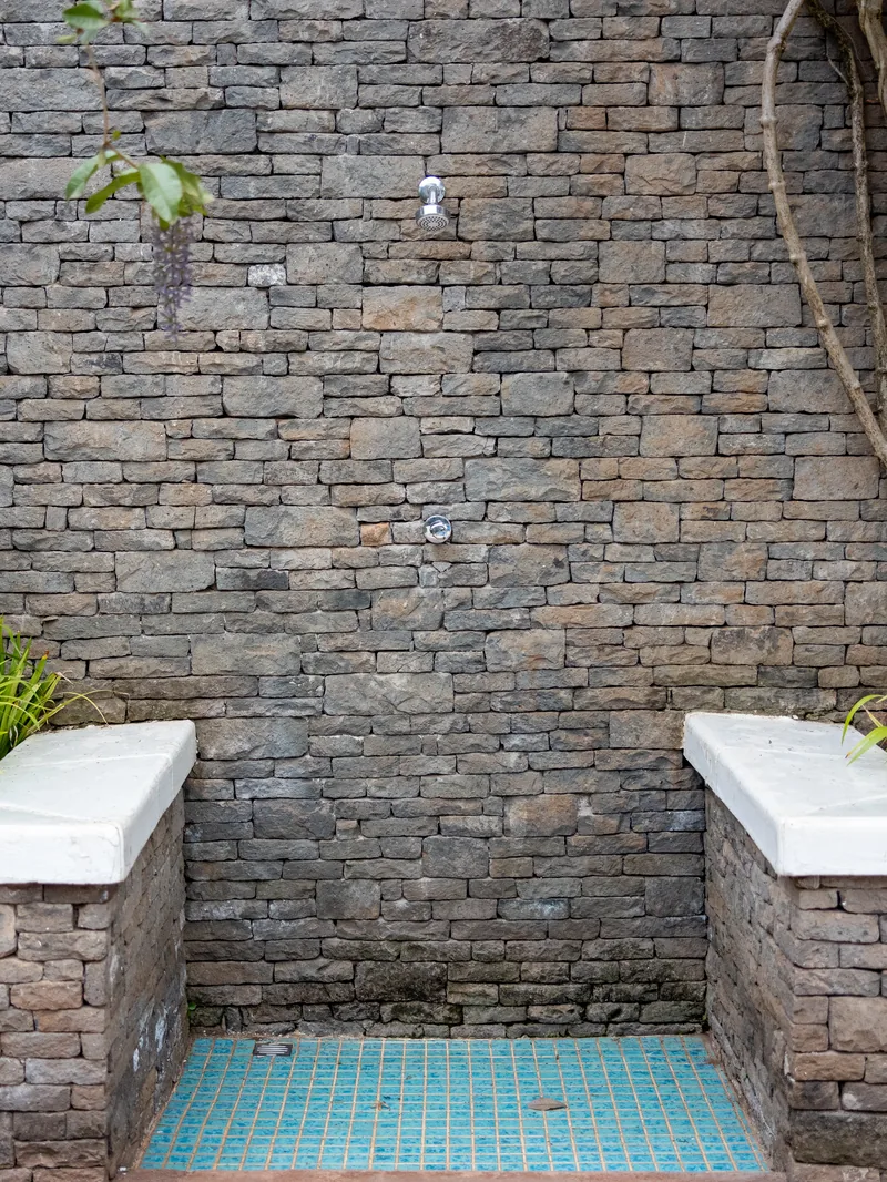 La douche extérieure de la Villa des Pins, mur de pierre et mosaïque turquoise
