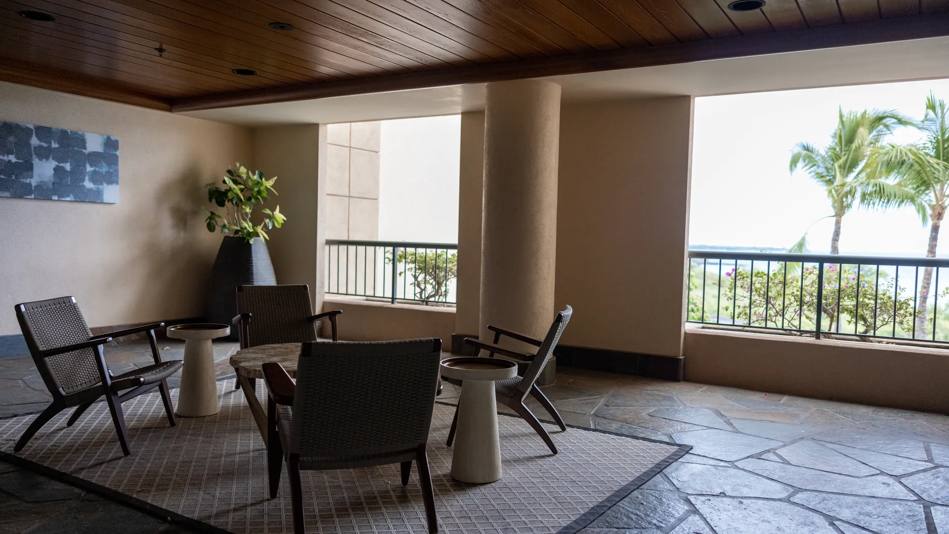 La terrasse couverte de l'Appartement Plage, fauteuils face aux palmiers
