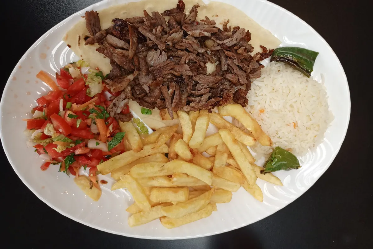 Assiette de bœuf de la broche avec frites, riz, salade de tomates et piments grillés