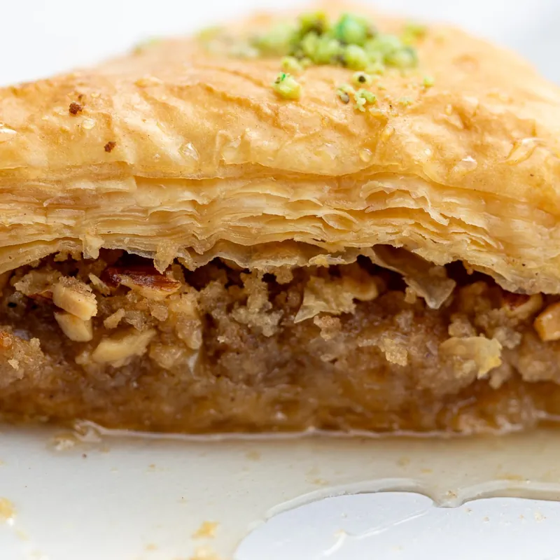 Part de baklava feuilletée, garnie de noix et nappée de miel