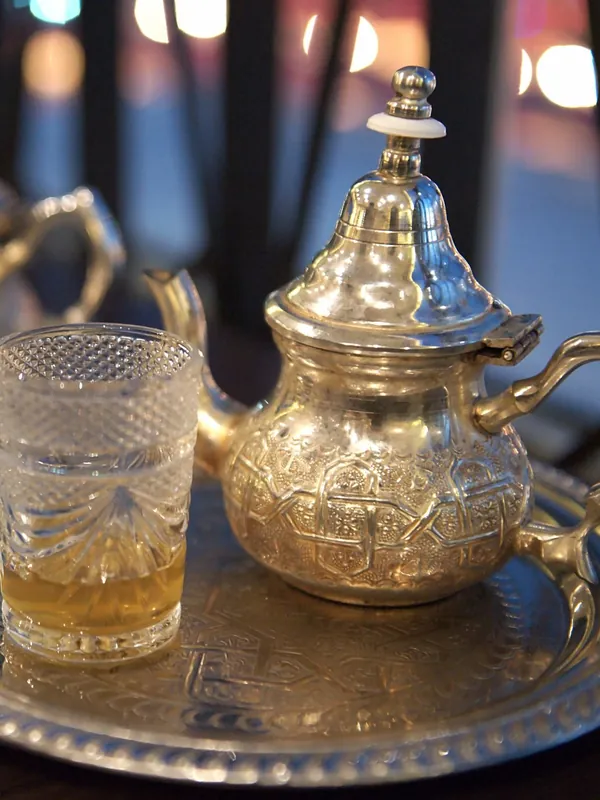 Théière en métal ciselé et verre de thé à la menthe sur un plateau