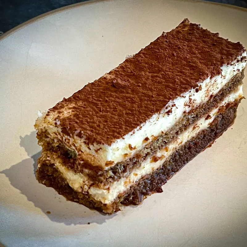 Part de tiramisu poudrée de cacao sur une assiette